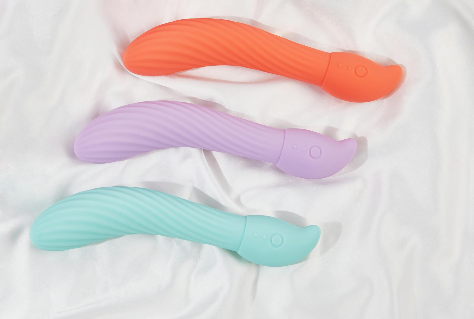 Three colorful vibrators arranged on white fabric, showcasing smooth suction technology
