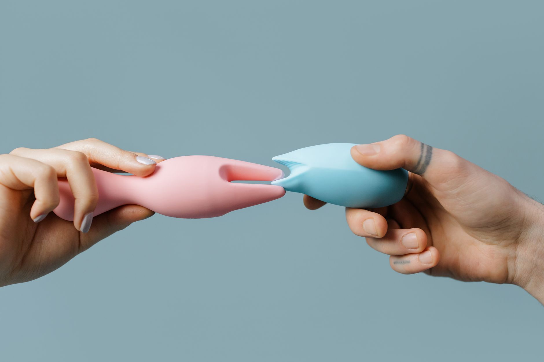 Close-up of hands holding a blue personal massager against a knitted sweater