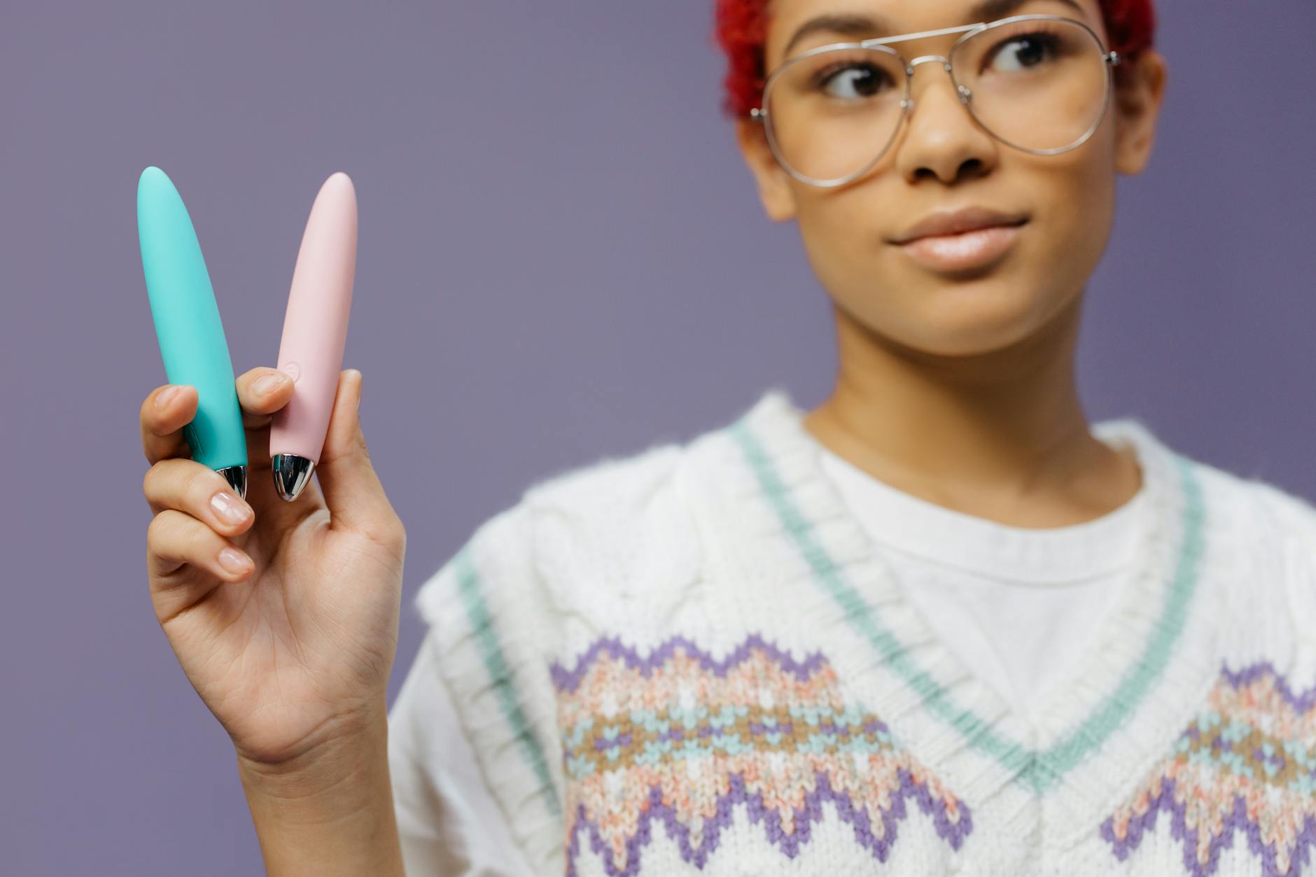 A woman holds colorful lemon clitoral vibrators against a purple background, symbolizing modern midlife pleasure exploration.