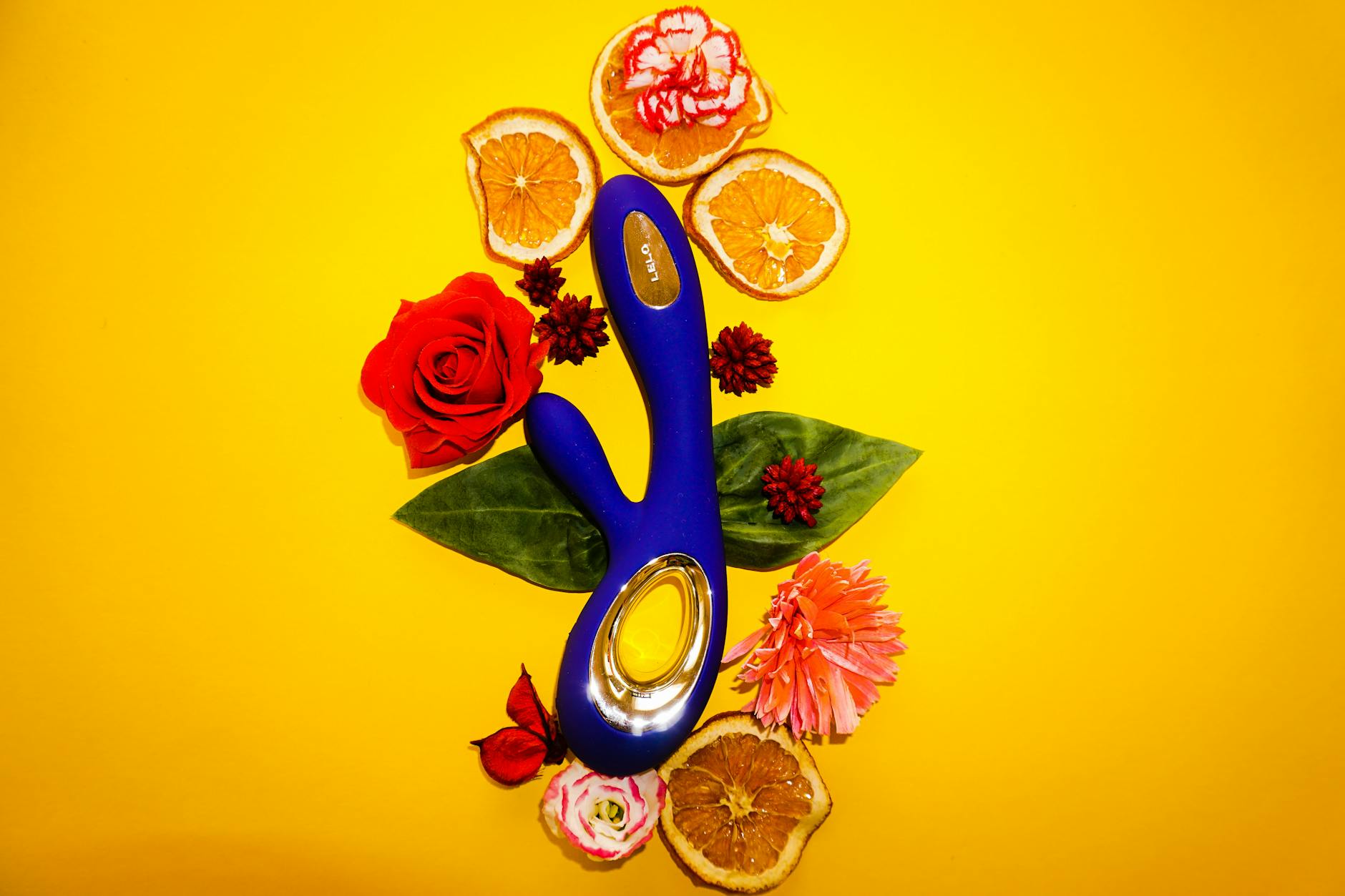Colorful adult toys including clitoral vibrators displayed on a bright yellow background, showcasing different designs and styles